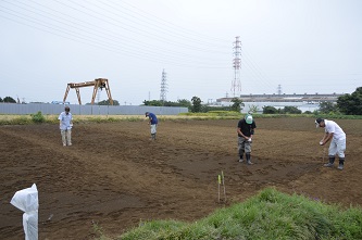 幼稚園児が種蒔きを終えたあとを修正している大人の写真