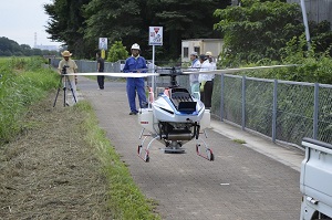 コスモスの種を蒔き終えた無人ヘリが道路に着陸した所の写真